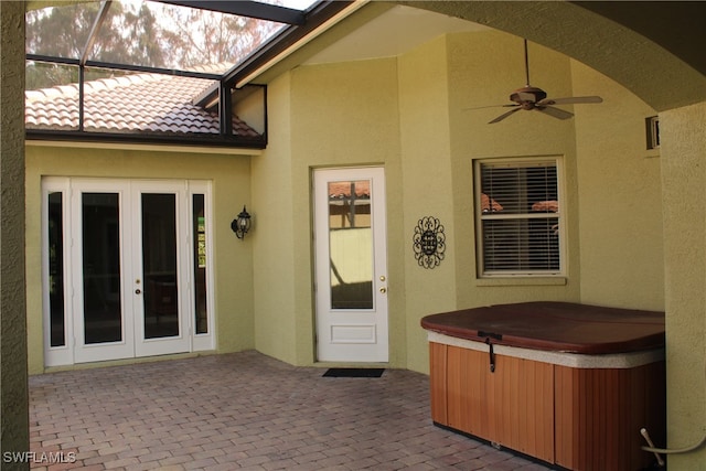 view of patio featuring a hot tub, glass enclosure, and ceiling fan