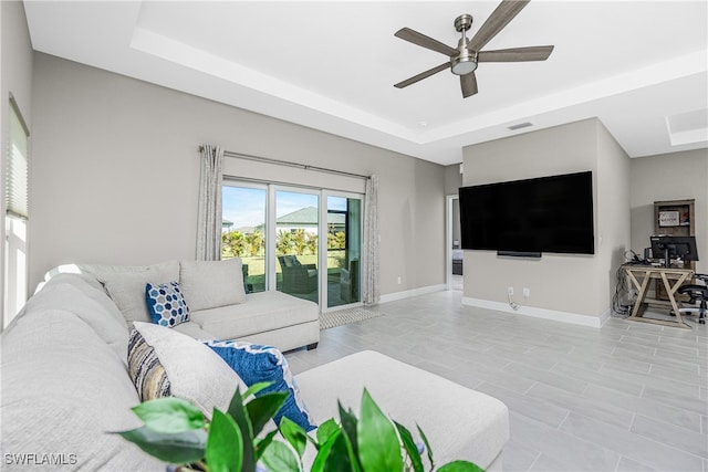 living room featuring ceiling fan and a raised ceiling