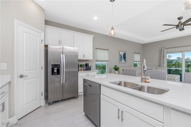 kitchen featuring light stone countertops, sink, stainless steel appliances, decorative light fixtures, and white cabinets