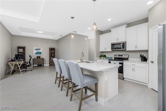 kitchen with hanging light fixtures, a center island with sink, a breakfast bar area, appliances with stainless steel finishes, and sink