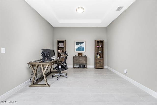 tiled office space featuring a tray ceiling