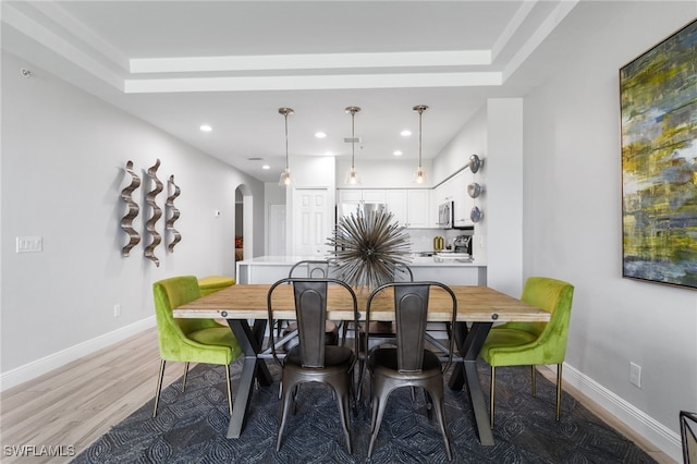 dining space with light hardwood / wood-style floors and a tray ceiling