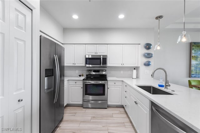 kitchen with sink, white cabinetry, stainless steel appliances, decorative light fixtures, and decorative backsplash