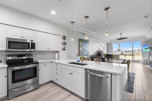 kitchen featuring kitchen peninsula, white cabinets, light hardwood / wood-style flooring, sink, and stainless steel appliances