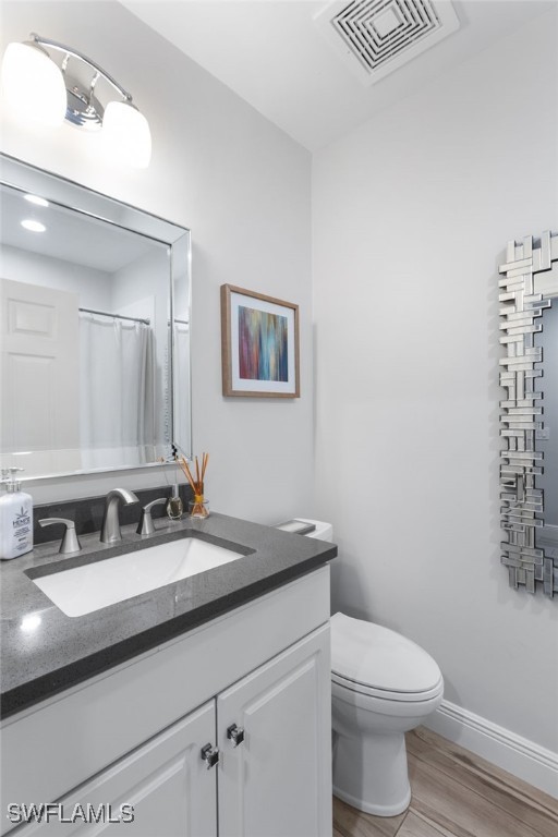 bathroom with vanity, hardwood / wood-style flooring, and toilet