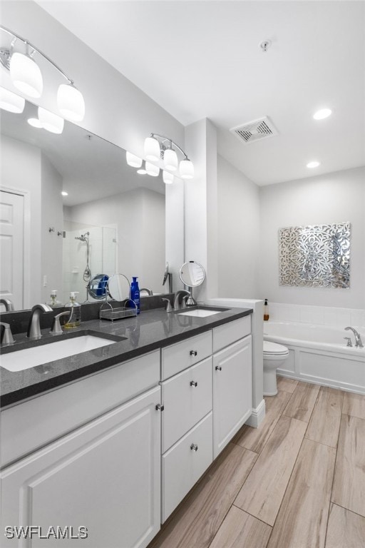 full bathroom with vanity, toilet, hardwood / wood-style flooring, and independent shower and bath