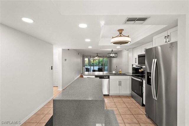 kitchen featuring appliances with stainless steel finishes, white cabinets, sink, and a raised ceiling