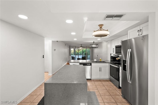 kitchen with stainless steel appliances, white cabinetry, sink, and a tray ceiling