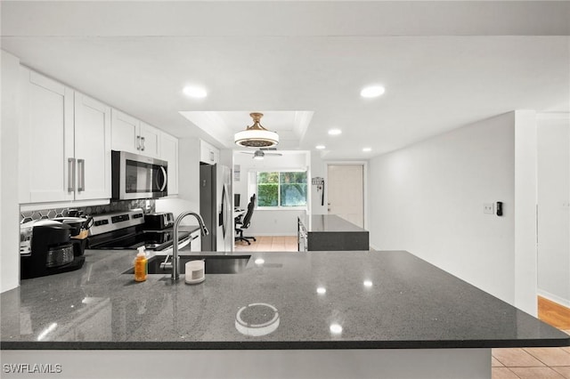 kitchen featuring appliances with stainless steel finishes, sink, white cabinets, dark stone counters, and a raised ceiling