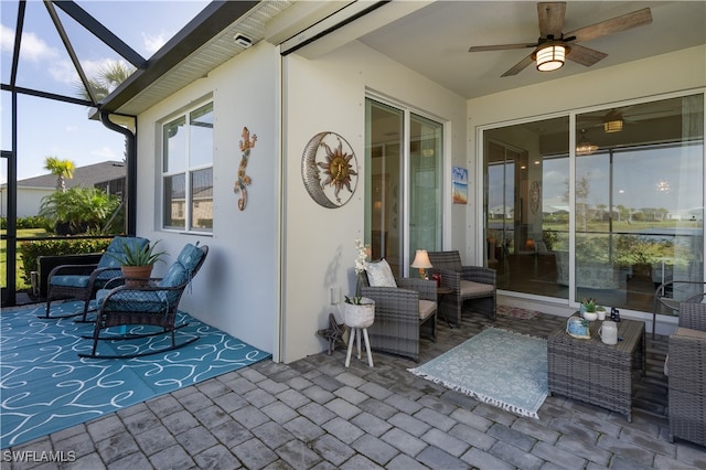 view of patio / terrace with ceiling fan, glass enclosure, and an outdoor living space