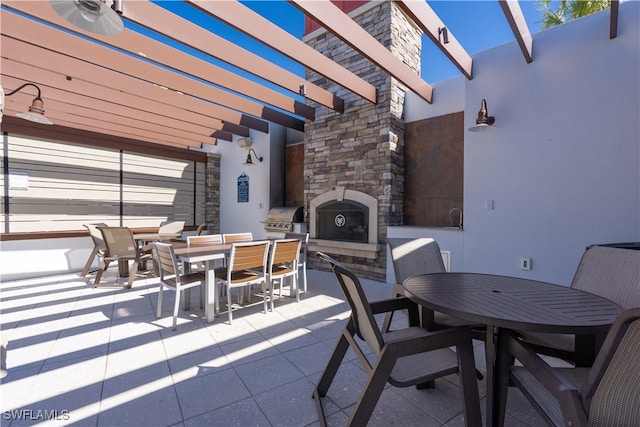 view of patio / terrace with an outdoor stone fireplace, a grill, and a pergola