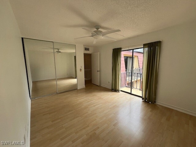 unfurnished bedroom featuring ceiling fan, a closet, a textured ceiling, and light wood-type flooring