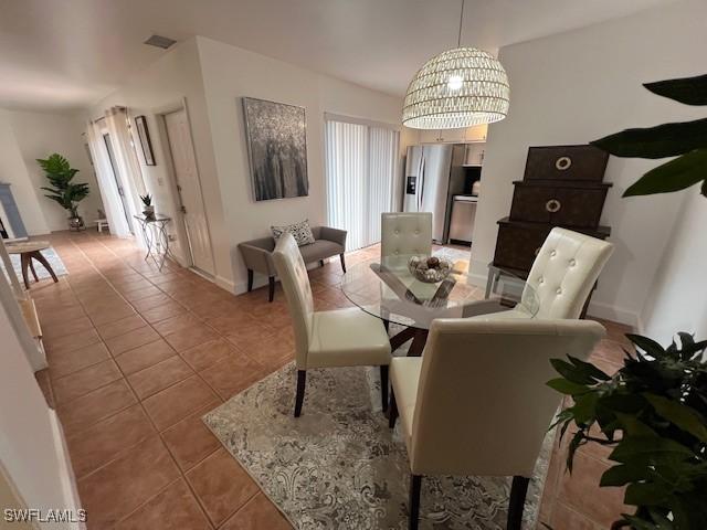 dining space featuring light tile patterned floors and a notable chandelier