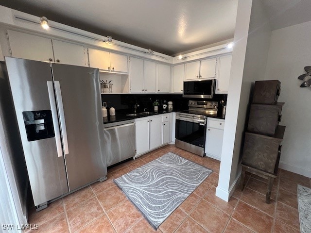 kitchen with tasteful backsplash, sink, white cabinets, and appliances with stainless steel finishes