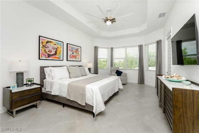 bedroom featuring light tile patterned flooring, ceiling fan, and a raised ceiling