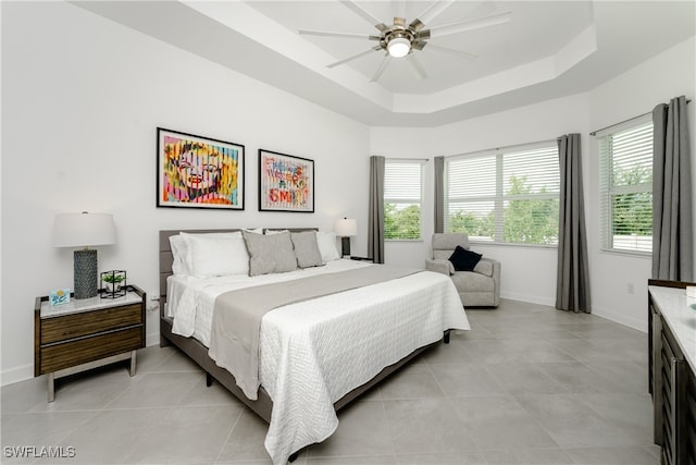 bedroom with ceiling fan, a raised ceiling, and light tile patterned floors