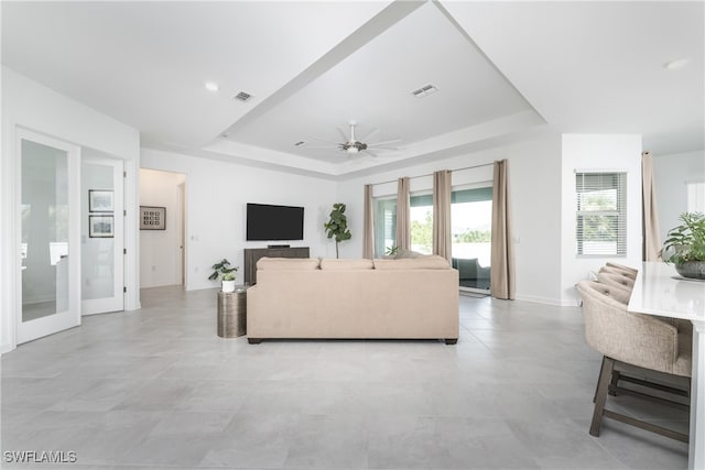 living room with ceiling fan and a raised ceiling