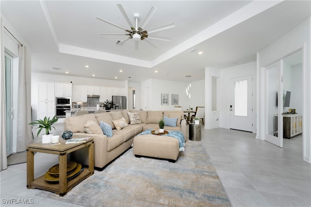 living room featuring ceiling fan and a raised ceiling