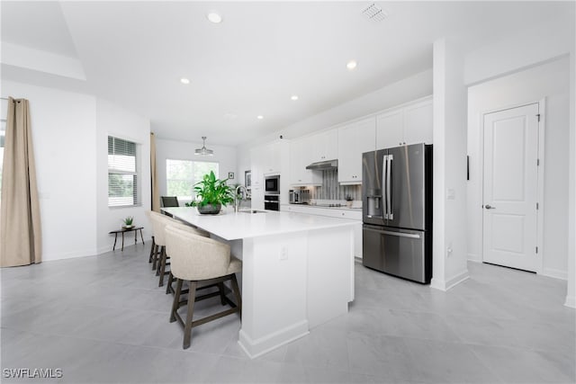 kitchen featuring stainless steel appliances, sink, a large island, a breakfast bar, and white cabinetry