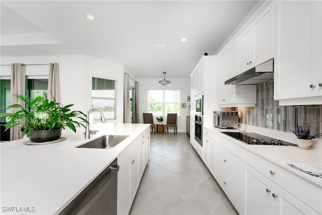 kitchen with tasteful backsplash, pendant lighting, sink, white cabinets, and black electric cooktop