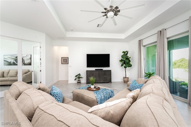 living room featuring ceiling fan, light tile patterned floors, and a tray ceiling