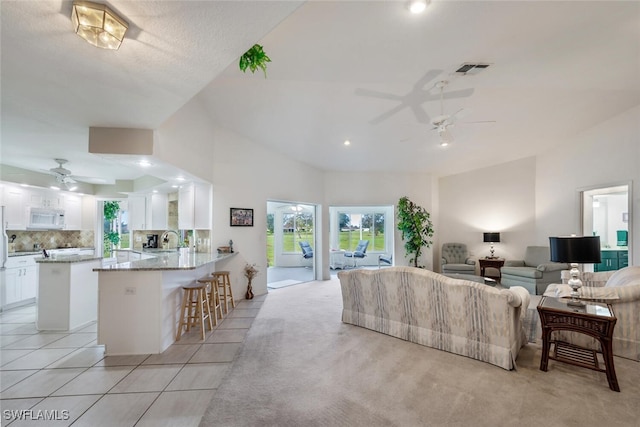 carpeted living room with sink, vaulted ceiling, and ceiling fan