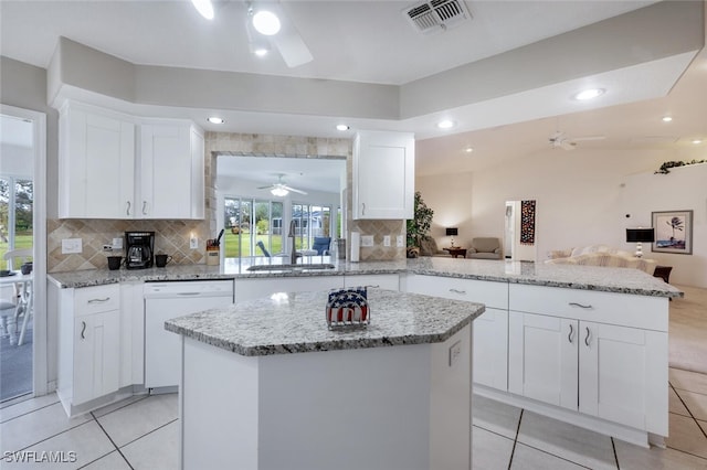 kitchen featuring kitchen peninsula, dishwasher, white cabinets, and a kitchen island