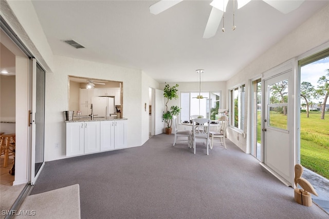 unfurnished sunroom featuring ceiling fan and plenty of natural light