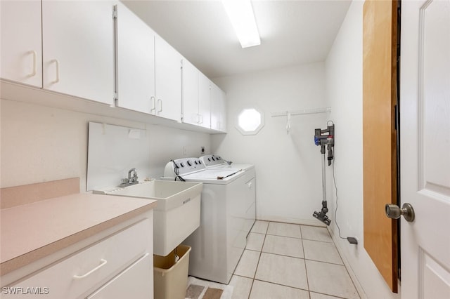 laundry room with light tile patterned flooring, washing machine and dryer, and cabinets