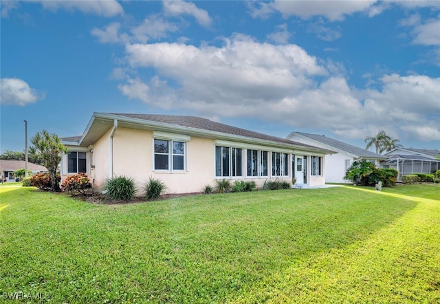 rear view of house with a lawn and a lanai