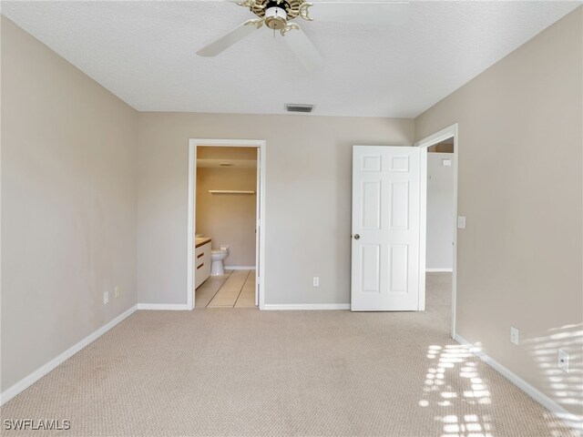 unfurnished bedroom featuring ceiling fan, ensuite bathroom, light carpet, and a textured ceiling