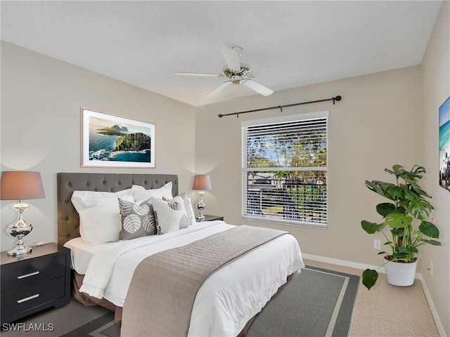 bedroom with ceiling fan, carpet, and a textured ceiling