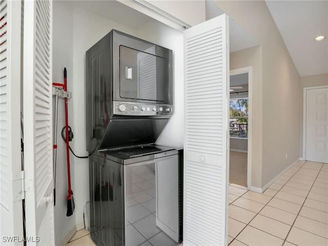 laundry area with stacked washer / drying machine and light tile patterned floors