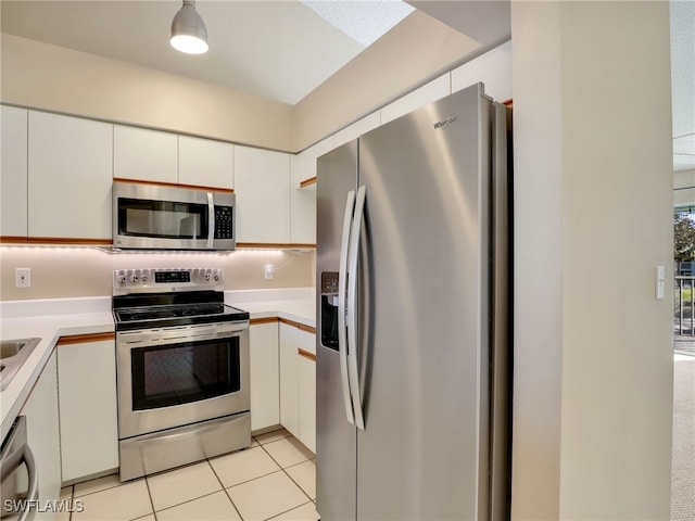 kitchen featuring tasteful backsplash, white cabinets, light tile patterned floors, and appliances with stainless steel finishes