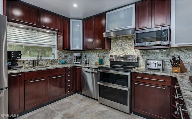 kitchen featuring light stone countertops, appliances with stainless steel finishes, tasteful backsplash, and sink