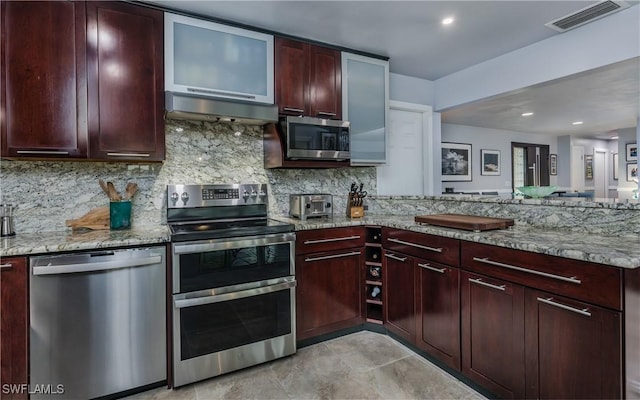 kitchen with stainless steel appliances, tasteful backsplash, light stone counters, kitchen peninsula, and extractor fan