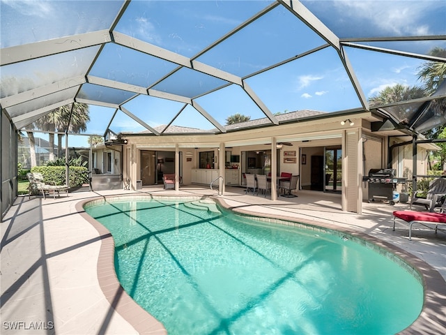 view of swimming pool featuring area for grilling, a patio, glass enclosure, and ceiling fan