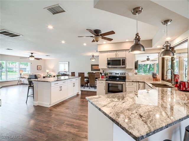 kitchen with sink, white cabinetry, stainless steel appliances, decorative light fixtures, and dark hardwood / wood-style floors