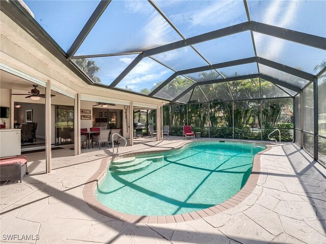 view of pool featuring a patio, ceiling fan, and glass enclosure