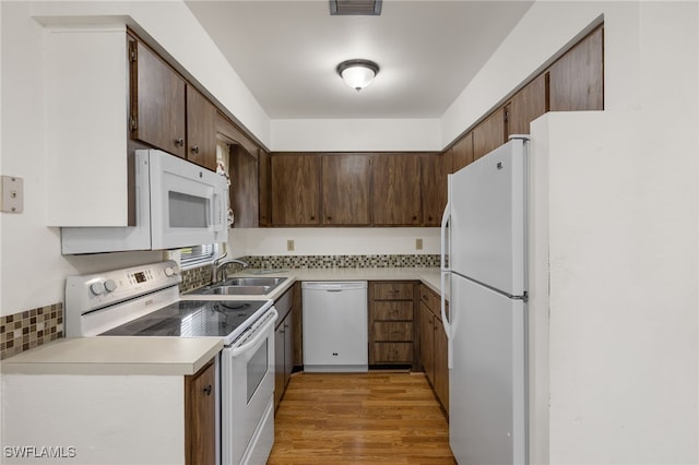 kitchen featuring sink, light hardwood / wood-style floors, white appliances, and tasteful backsplash