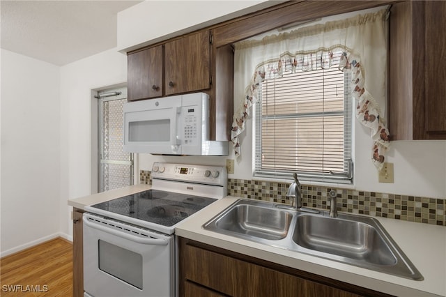 kitchen featuring decorative backsplash, white appliances, sink, dark brown cabinetry, and light hardwood / wood-style floors