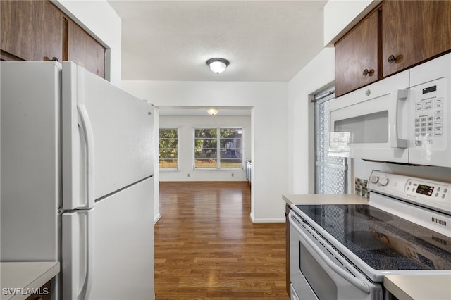 kitchen with white appliances, a textured ceiling, and dark hardwood / wood-style flooring