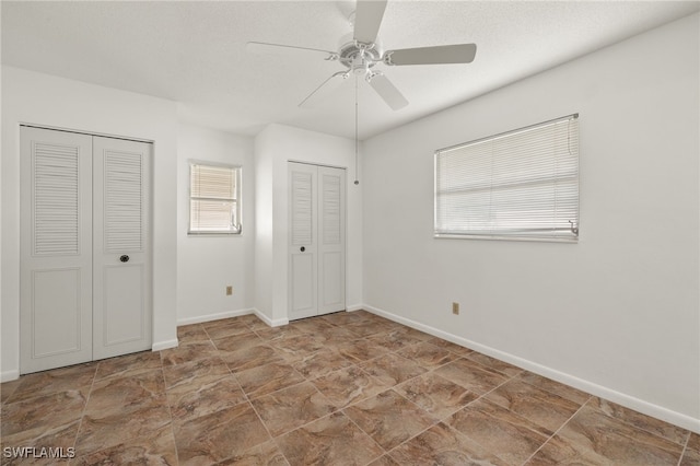 unfurnished bedroom featuring multiple closets, a textured ceiling, and ceiling fan