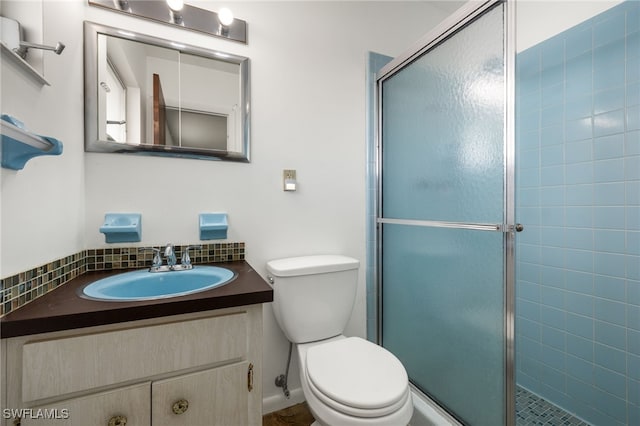 bathroom featuring vanity, a shower with shower door, and toilet