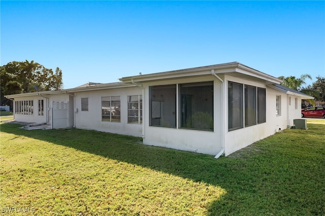 rear view of house featuring a yard and a sunroom