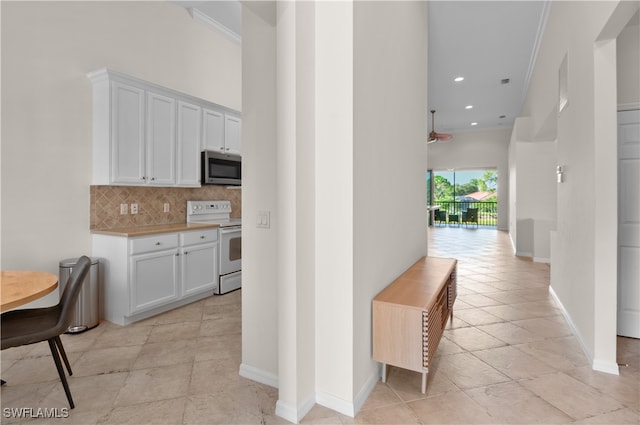 kitchen with ornamental molding, decorative backsplash, white cabinets, and white electric stove