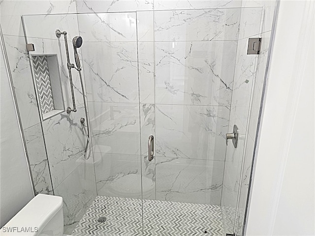 bathroom with a shower with shower door and toilet