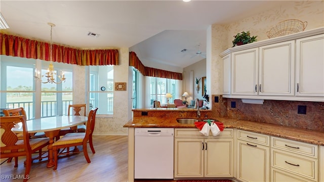 kitchen featuring dishwasher, sink, light stone countertops, an inviting chandelier, and light hardwood / wood-style floors