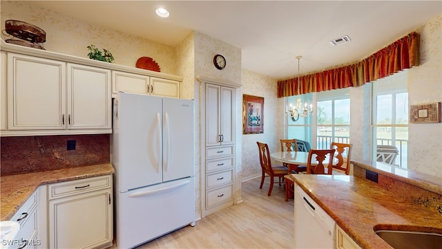 kitchen featuring white appliances, light wood-type flooring, cream cabinetry, pendant lighting, and a chandelier