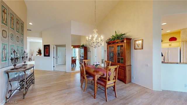 dining space featuring high vaulted ceiling, light hardwood / wood-style flooring, and a chandelier